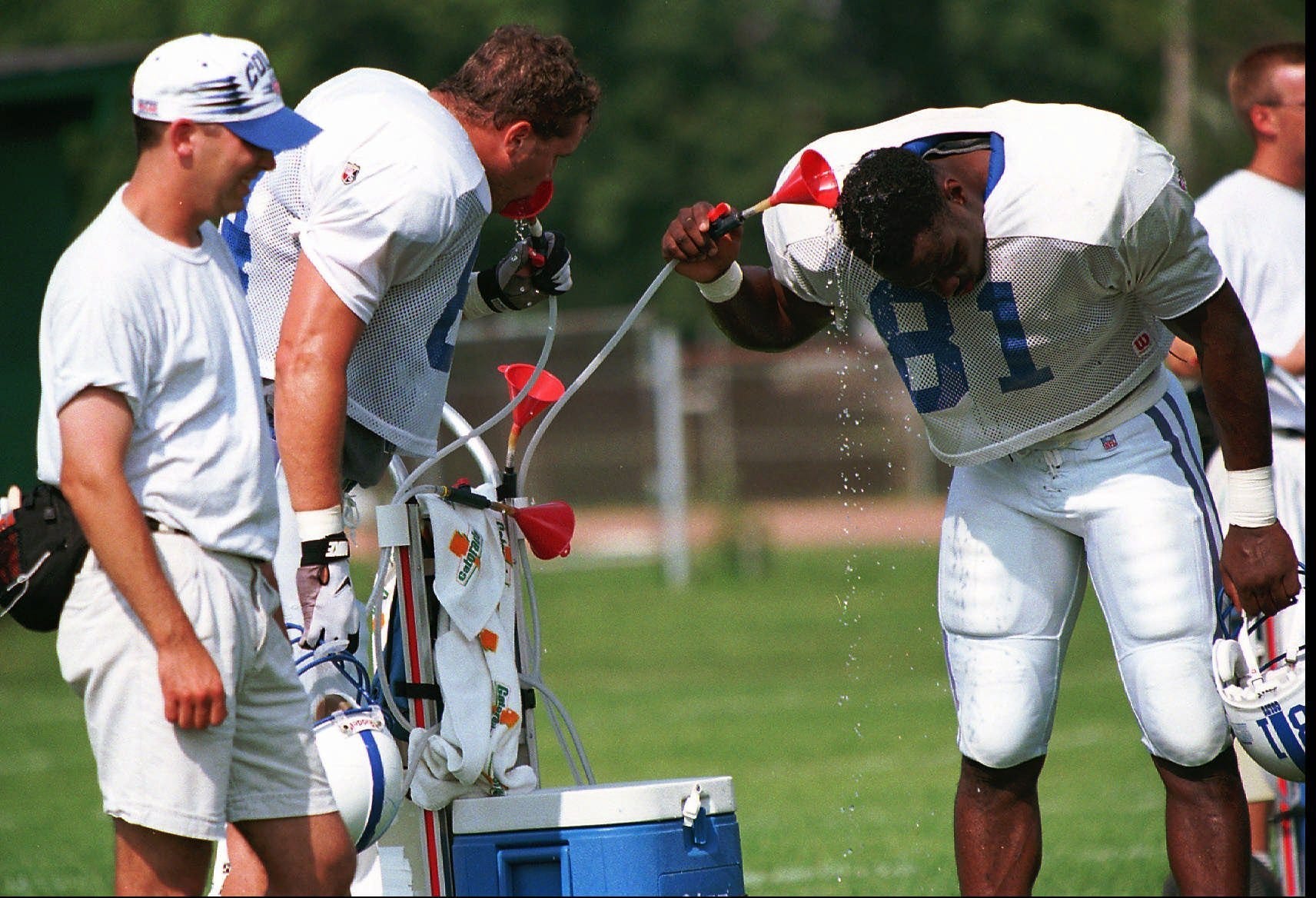 Indianapolis Colts tight end Scott Slutzker, left, takes a drink while fellow tight end Marcus Pollard takes a shower as they seek relief from the heat during drills Tuesday, Aug. 6, 1996, in Anderson, Ind. The Colts face another steamy two weeks at the training camp at Anderson University.