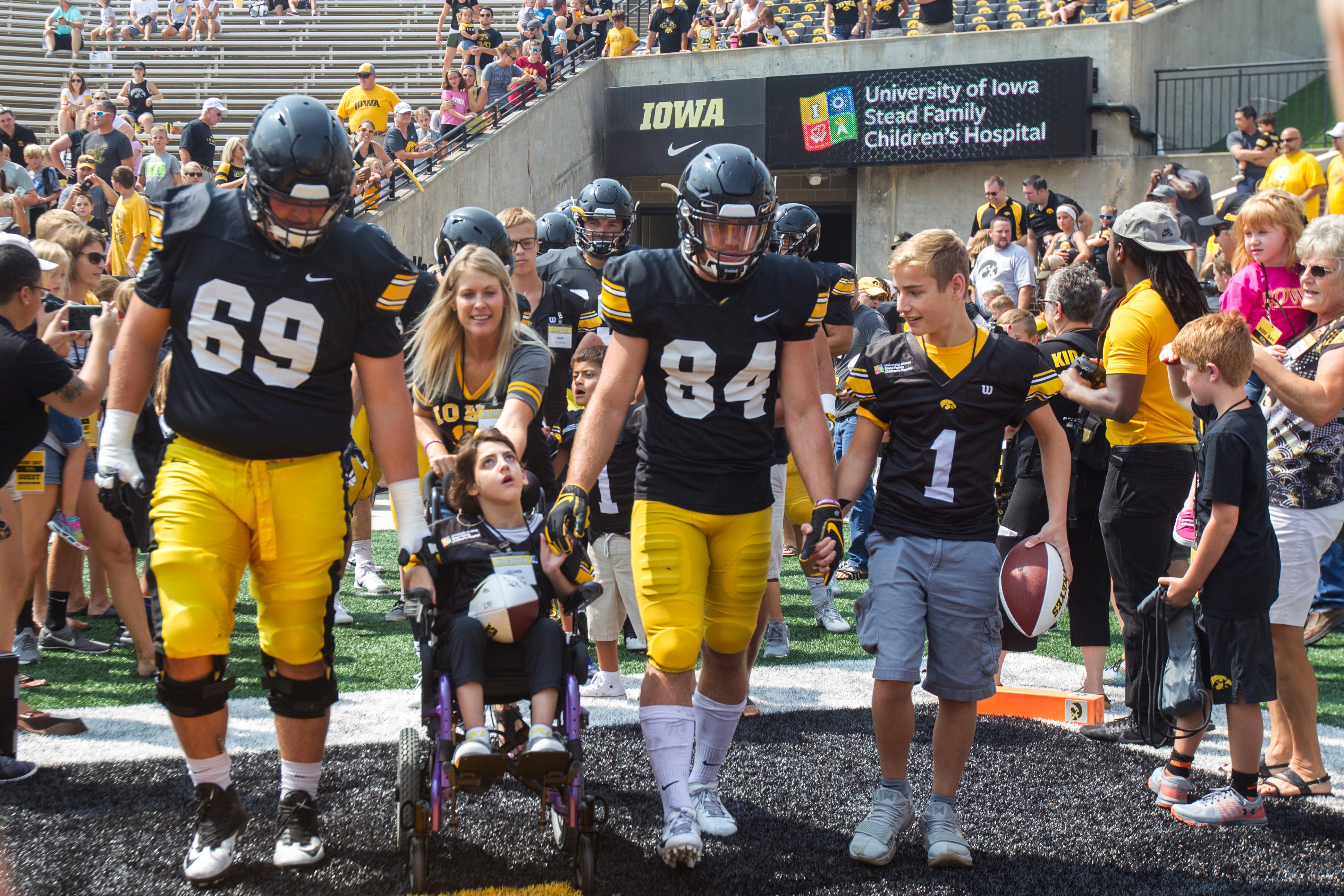 Iowa offensive lineman Keegan Render and wide receiver Nick Easley walk out of the tunnel with Kid Captains during a Kids Day practice on Saturday, Aug. 11, 2018, at Kinnick Stadium in Iowa City.