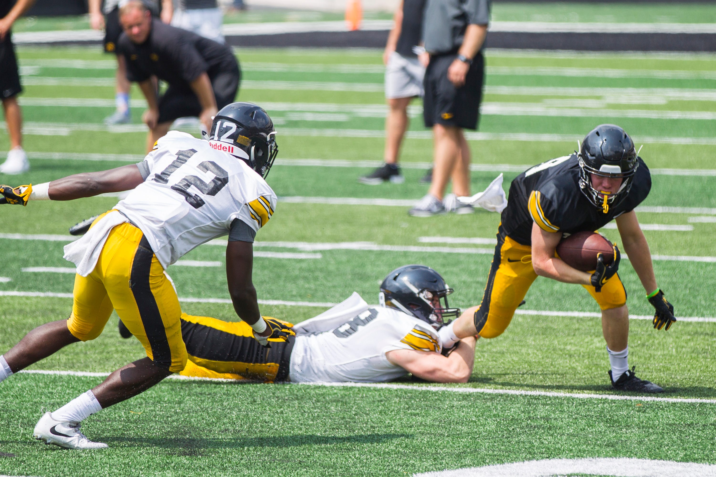 Iowa wide receiver Max Cooper attempts to shed a tackle from defensive back John Milani as D.J. Johnson (12) closes in during a Kids Day practice on Saturday, Aug. 11, 2018, at Kinnick Stadium in Iowa City.
