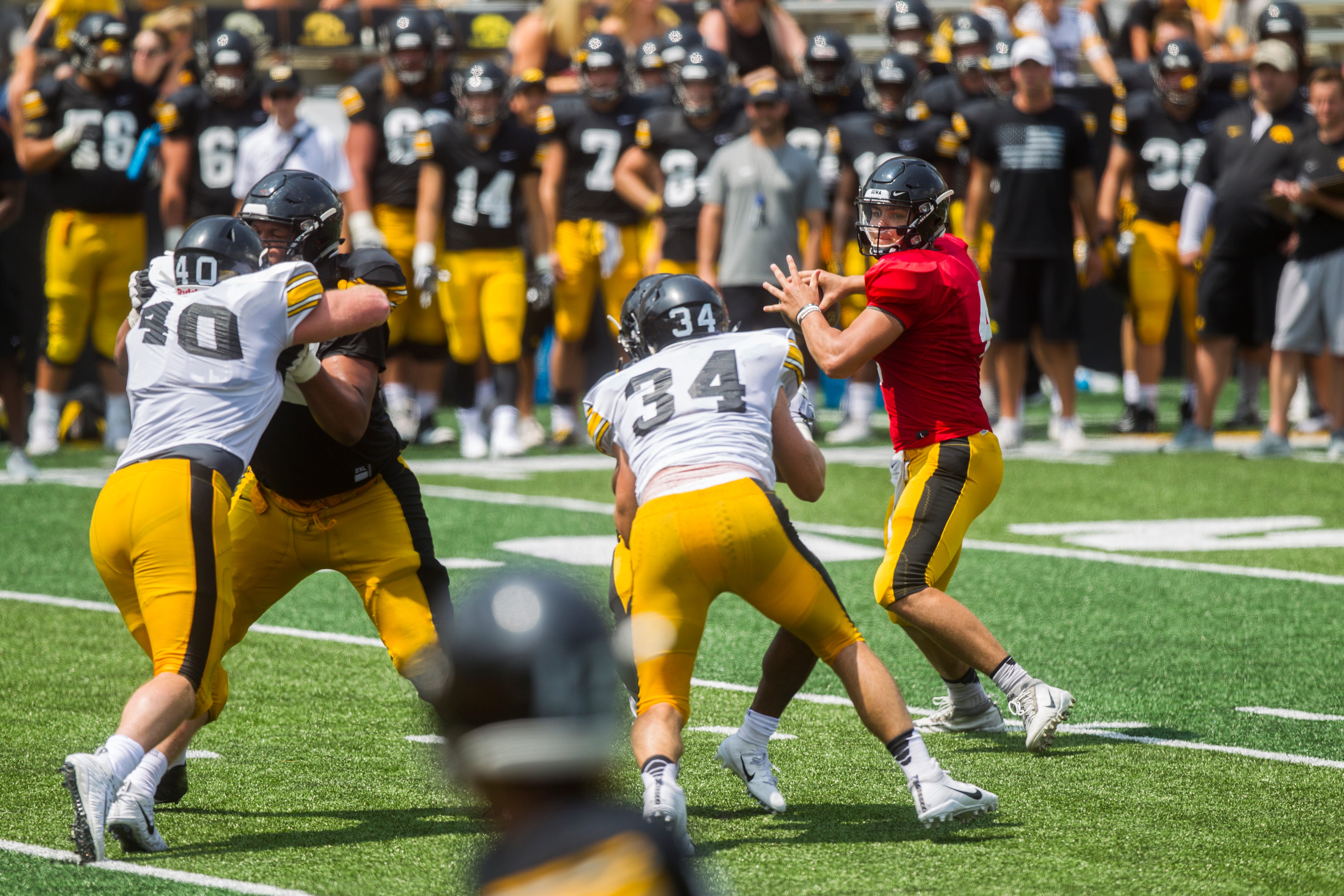 Iowa quarterback Nate Stanley looks to get a ball out while Iowa defensive end Parker Hesse and linebacker Kristian Welch try to get past blocks during a Kids Day practice on Saturday, Aug. 11, 2018, at Kinnick Stadium in Iowa City.