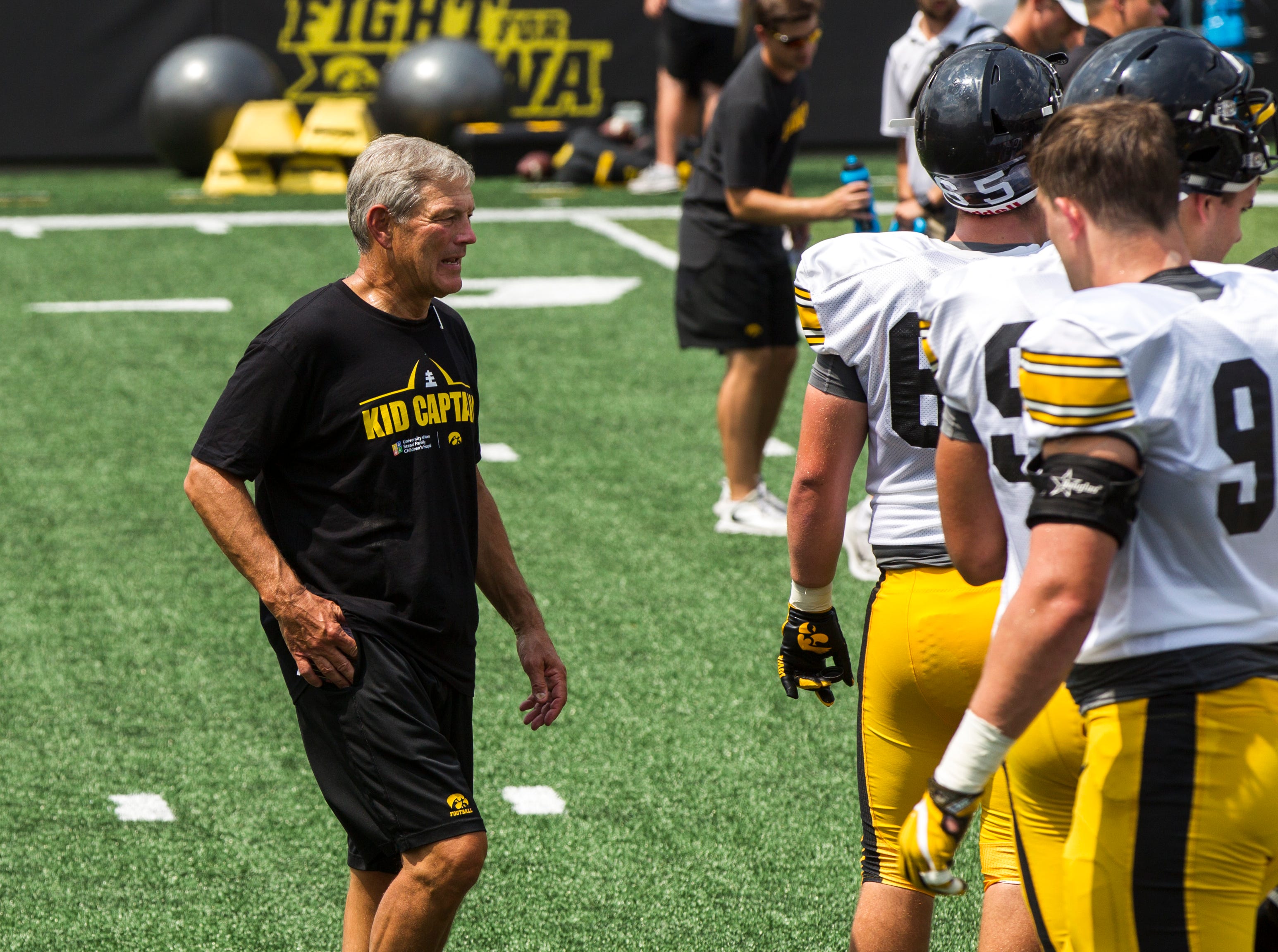 Iowa football head coach Kirk Ferentz talks with members of the defense during a Kids Day practice on Saturday, Aug. 11, 2018, at Kinnick Stadium in Iowa City.