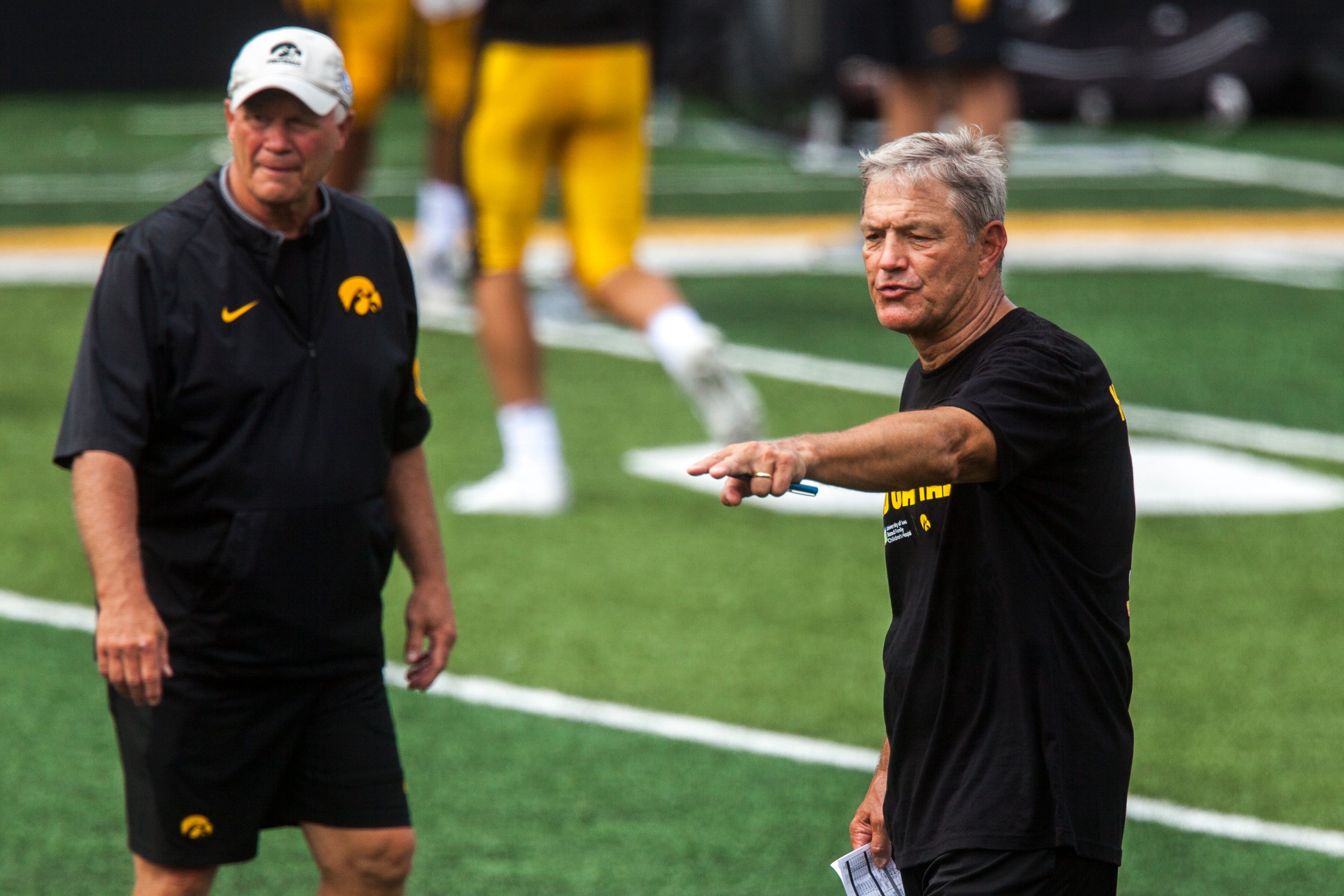 Iowa football head coach Kirk Ferentz (right) gestures during a Kids Day practice on Saturday, Aug. 11, 2018, at Kinnick Stadium in Iowa City.