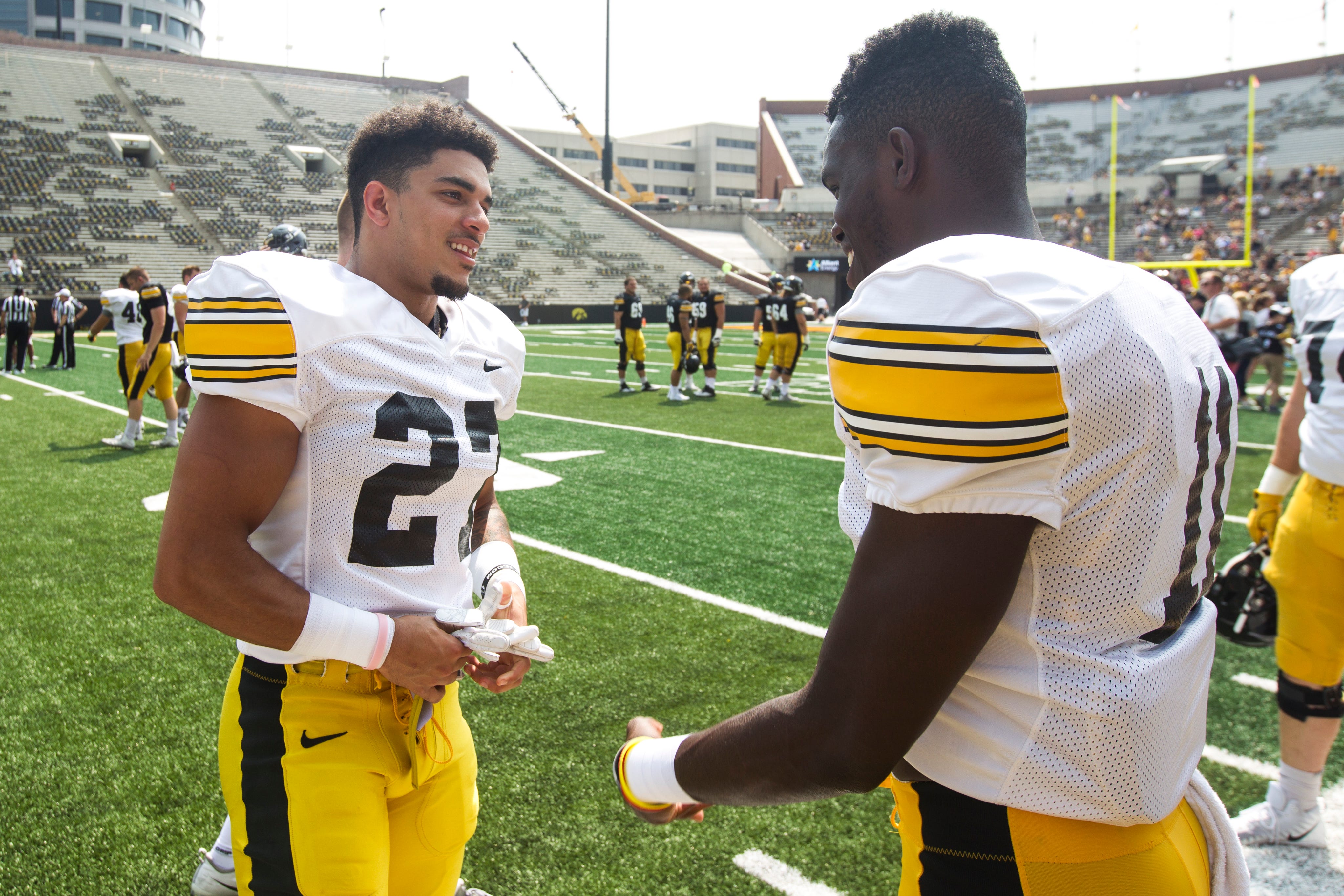 Iowa defensive back Amani Hooker (27) talks with teammate Michael Ojemudia (11) during a Kids Day practice on Saturday, Aug. 11, 2018, at Kinnick Stadium in Iowa City.