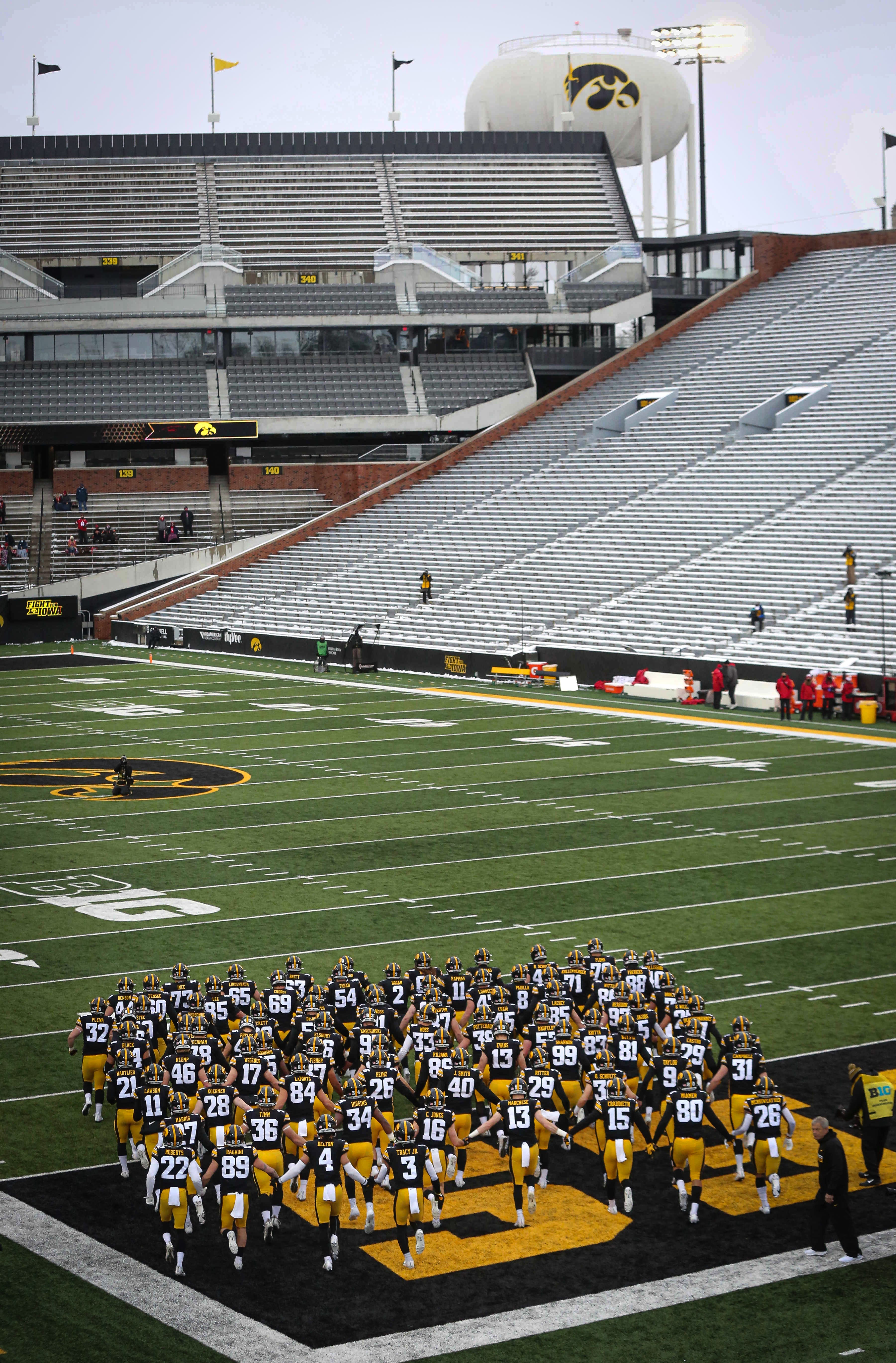 Members of the Iowa Hawkeyes football team take the field to an empty stadium prior to kickoff against Wisconsin on Saturday, Dec. 12, 2020, at Kinnick Stadium in Iowa City, Iowa.