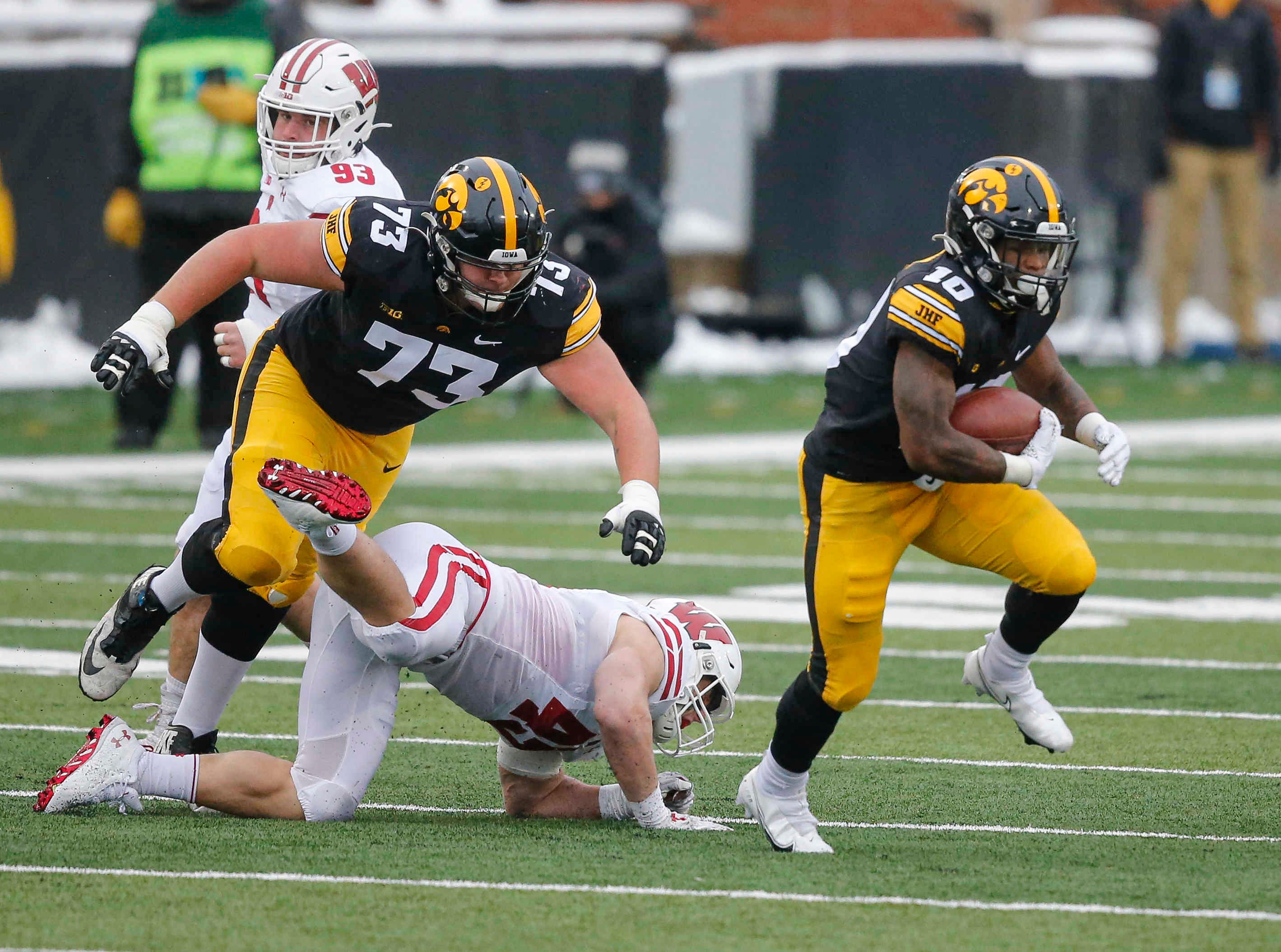 Iowa senior running back Mekhi Sargent runs the ball as left guard Cody Ince flattens a Wisconsin defender in the first quarter on Saturday, Dec. 12, 2020, at Kinnick Stadium in Iowa City, Iowa.