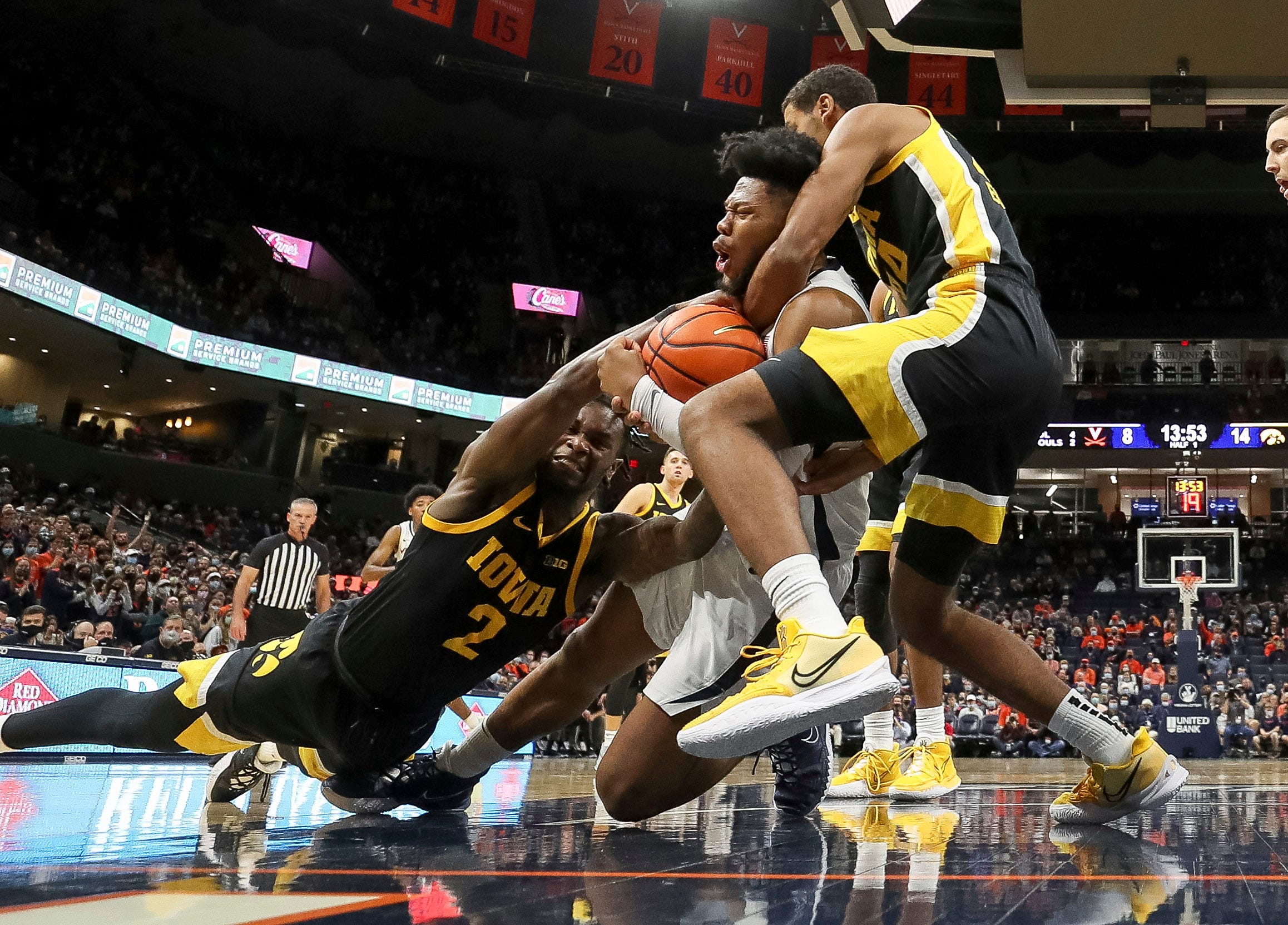 Virginia forward Jayden Gardner (1) is fouled fighting for a loose ball with Iowa guard Joe Toussaint (2) and Iowa forward Kris Murray (24) during the second half of an NCAA college basketball game, Monday, Nov. 29, 2021, in Charlottesville, Va.