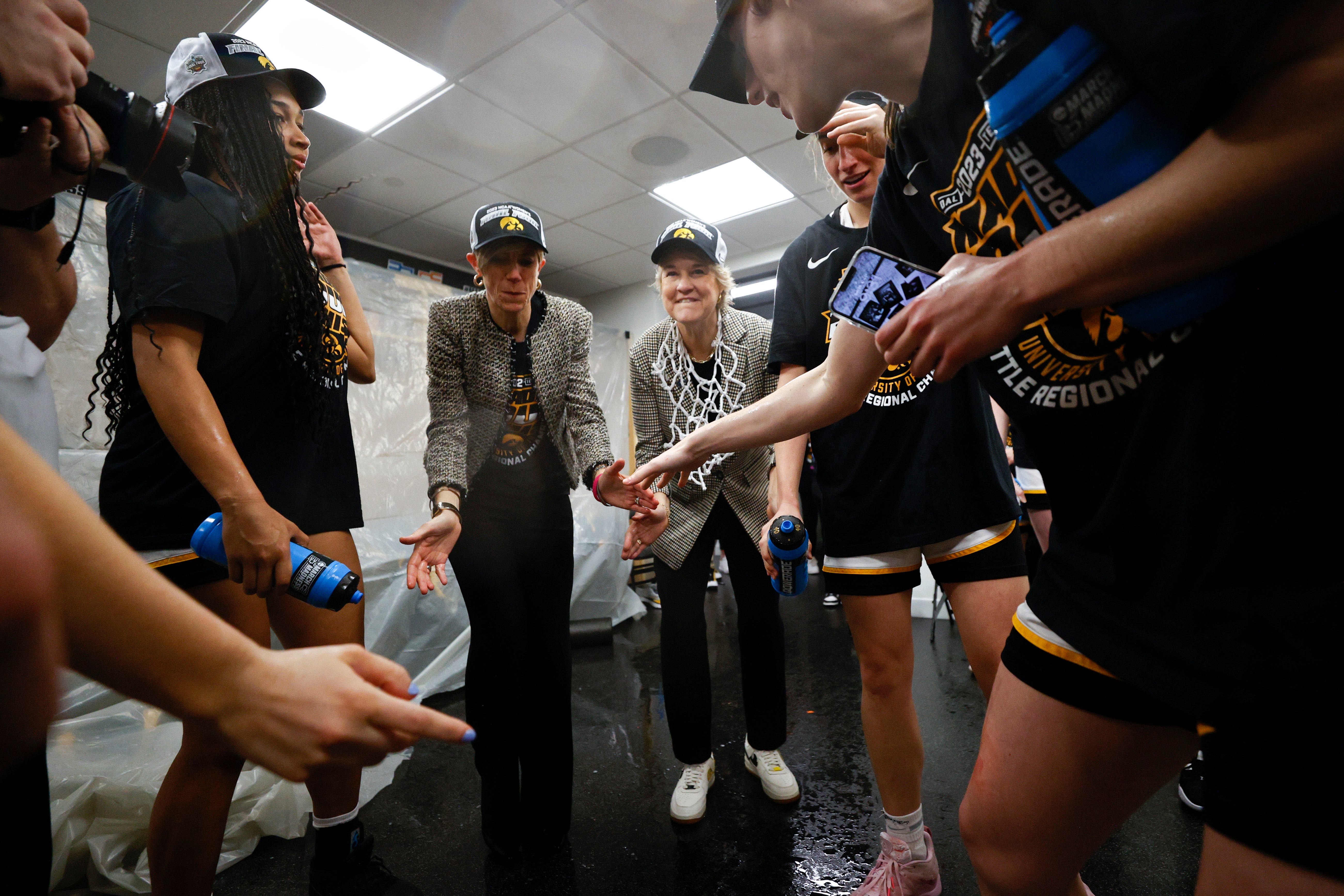 Iowa associate head coach Jan Jensen and head coach Lisa Bluder celebrate with players in the locker room after defeating the Louisville Cardinals 97-83 in the Elite Eight round of the NCAA Women's Basketball Tournament, March 26, 2023, at Climate Pledge Arena in Seattle.